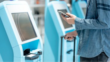 man at the self check in kiosk in airport terminal